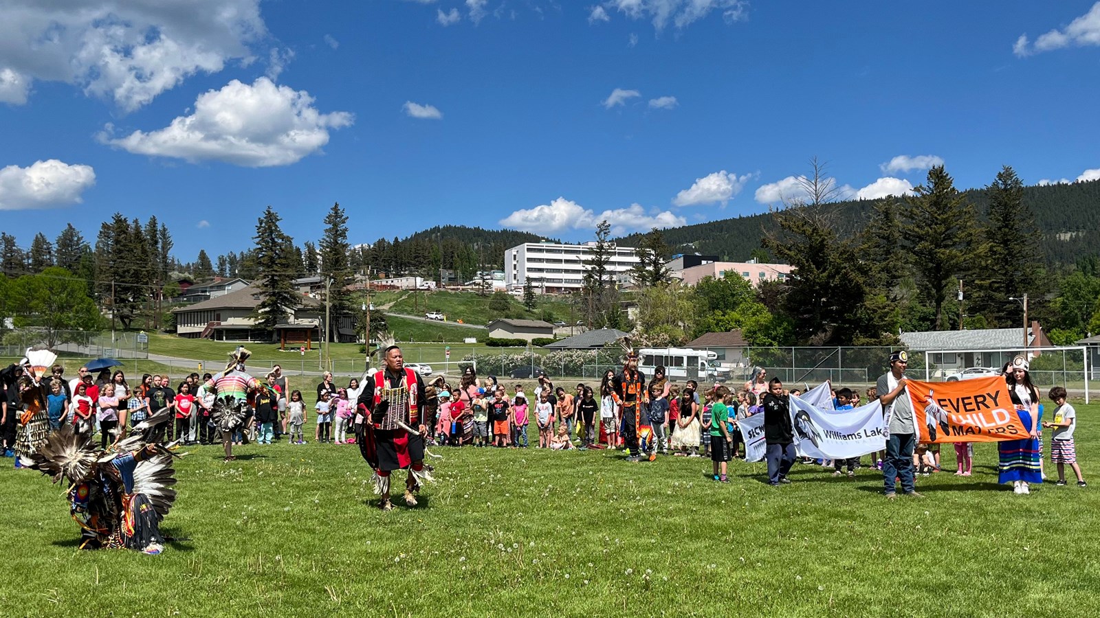 Image of the Marie Sharpe Pow Wow with dancers and an Every Child Matters banner.